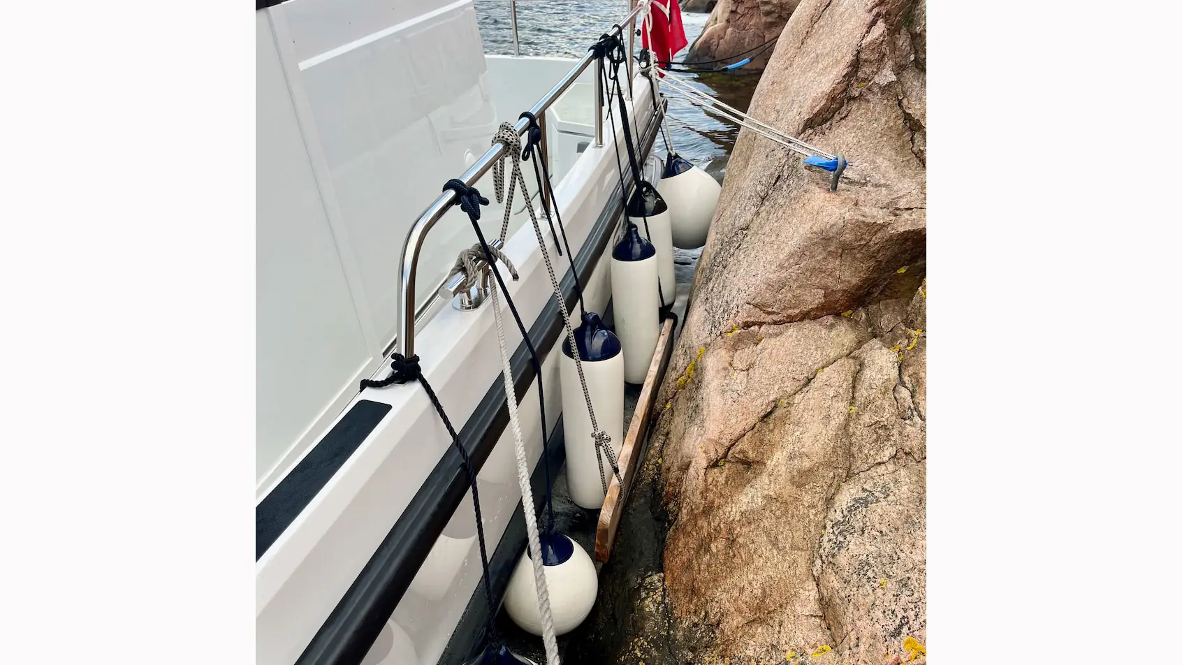 Fritidsbåt fortøyd ved fjellvegg, med fender